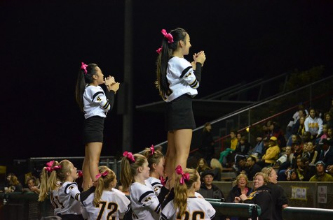 Juniors Ruby Li and Patricia Lee are held in a prep stunt while cheering at the Homecoming game. Cheerleaders practice four hours every week in order to perform at games year round.