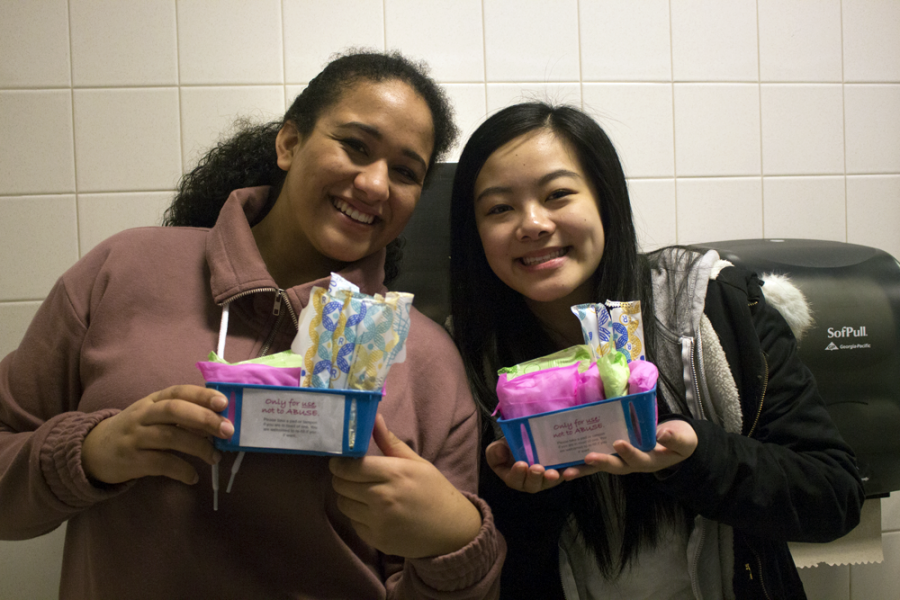 Juniors Kamaria Taylor (left) and Michelle Soi (right) pose with the baskets in the locker room bathroom. With the help of their families, they purchased all the supplies themselves. 