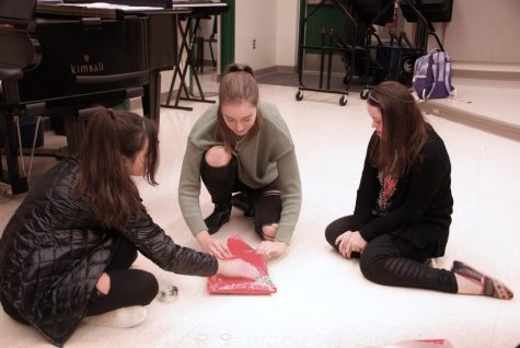 Sophomore Annalise Adad, senior Erin Mackey and senior Savannah Drollinger wrap a gift for the 'adopted' family. Newhall said that the in-class wrapping days were a great bonding experience for the class.