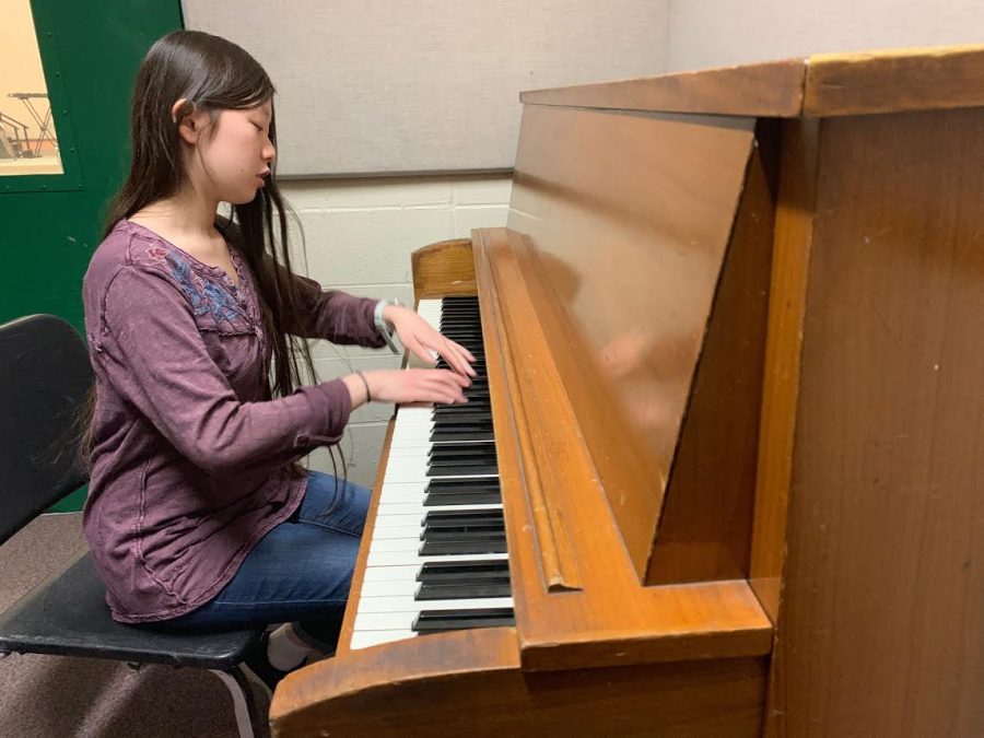 Junior Jenny Xiong warms up as she plays the piano in a practice room.