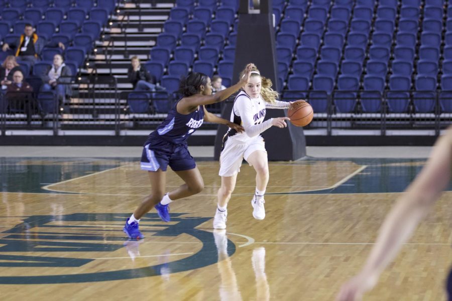 Junior Lucy Young dribbles up the court through a Rogers defender in round one of state. The Vikings advanced with a 65-54 overtime victory.