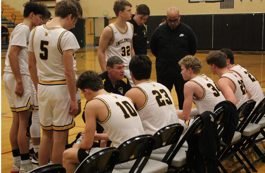 The boys varsity team huddles to listen to Coach Greg Lowell halfway into the game. The team beat Juanita 67-46 on Saturday, Dec. 7. Photo by Caden Pavlovski
