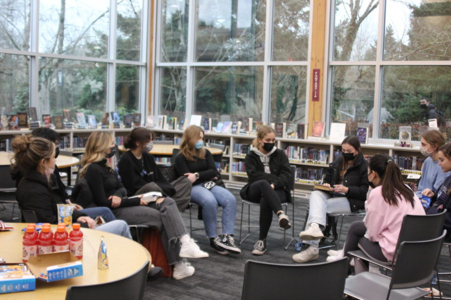 The members of the IHS book club meet in the corner of the library to discuss their current novel of the month. 