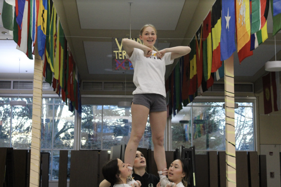 Junior Chloe Vancour (she/her) making a pose in the flyer position while
practicing their full-out routine.