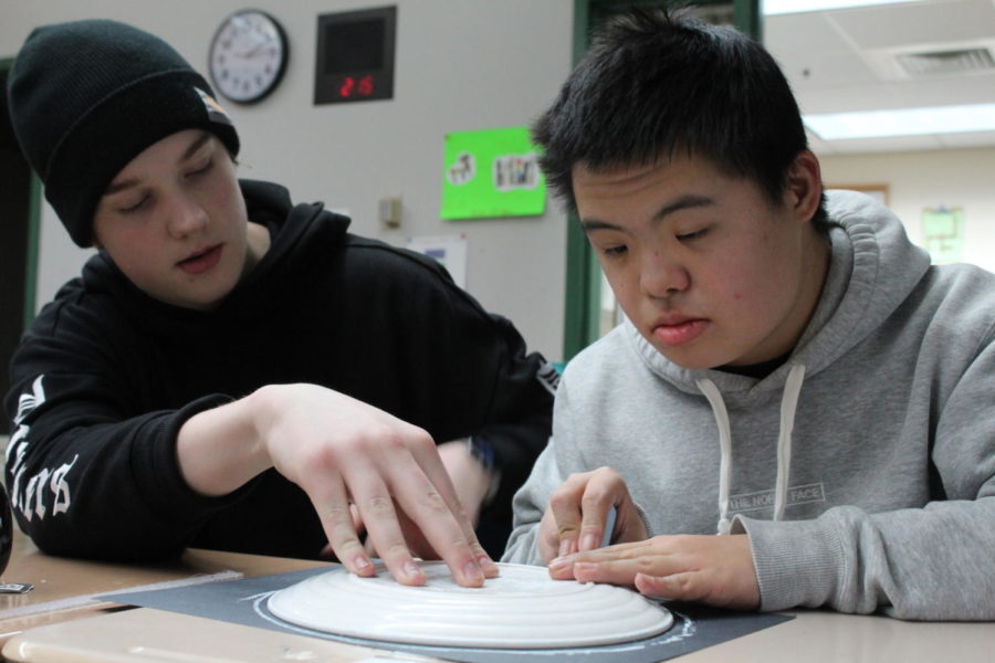 Senior Owen Jones (he/him) helps sophomore Satoshi Takeuchi (he/him) trace out a circle as they make a moon painting during seventh period on Jan. 12.