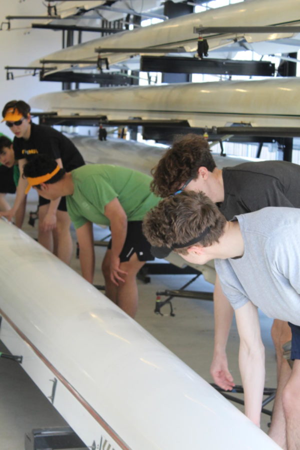 From left to right, crew teammates Stian Blockhus, Will Moore, Vincent Haug, Victor Agbayani, Jack Krey and Drew Hermes  pick their boat up to carry it out to water on March 17. 