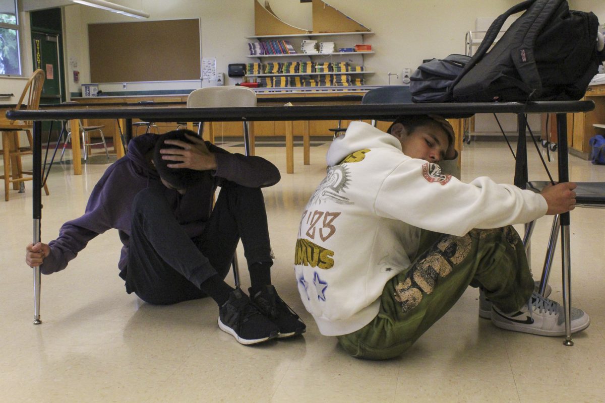 Junior Grant Wotherspoon and Junior Jaxon Coburn simulate what they are taught to do during an earthquake: duck under cover, hold on to a sturdy object and protect your head.