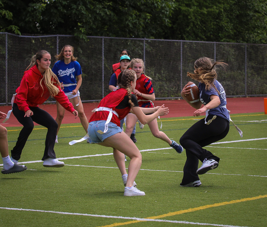 Senior Macie Looney spins out of the reach of defending freshman team players as she runs towards the endzone during the Empowerpuff game on June 11.