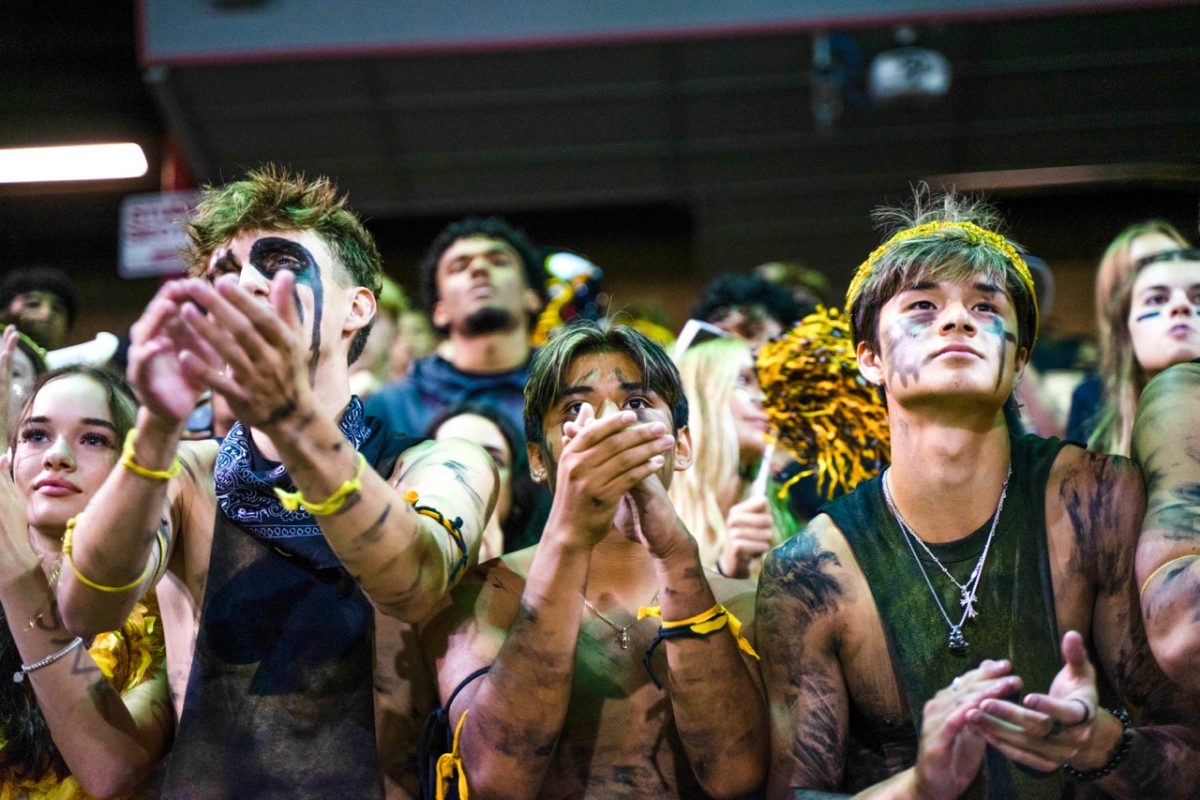 “The Suits” are an unofficial group of spirited students who cheer in the front row and go all out for games. At a football game on Sept. 14, members of The Suits, Monpas-Huber (left), Alex Arreola (center), who is an honorary member referred to as The Joker, and Mathieu Gioanni (right), lead the student section.