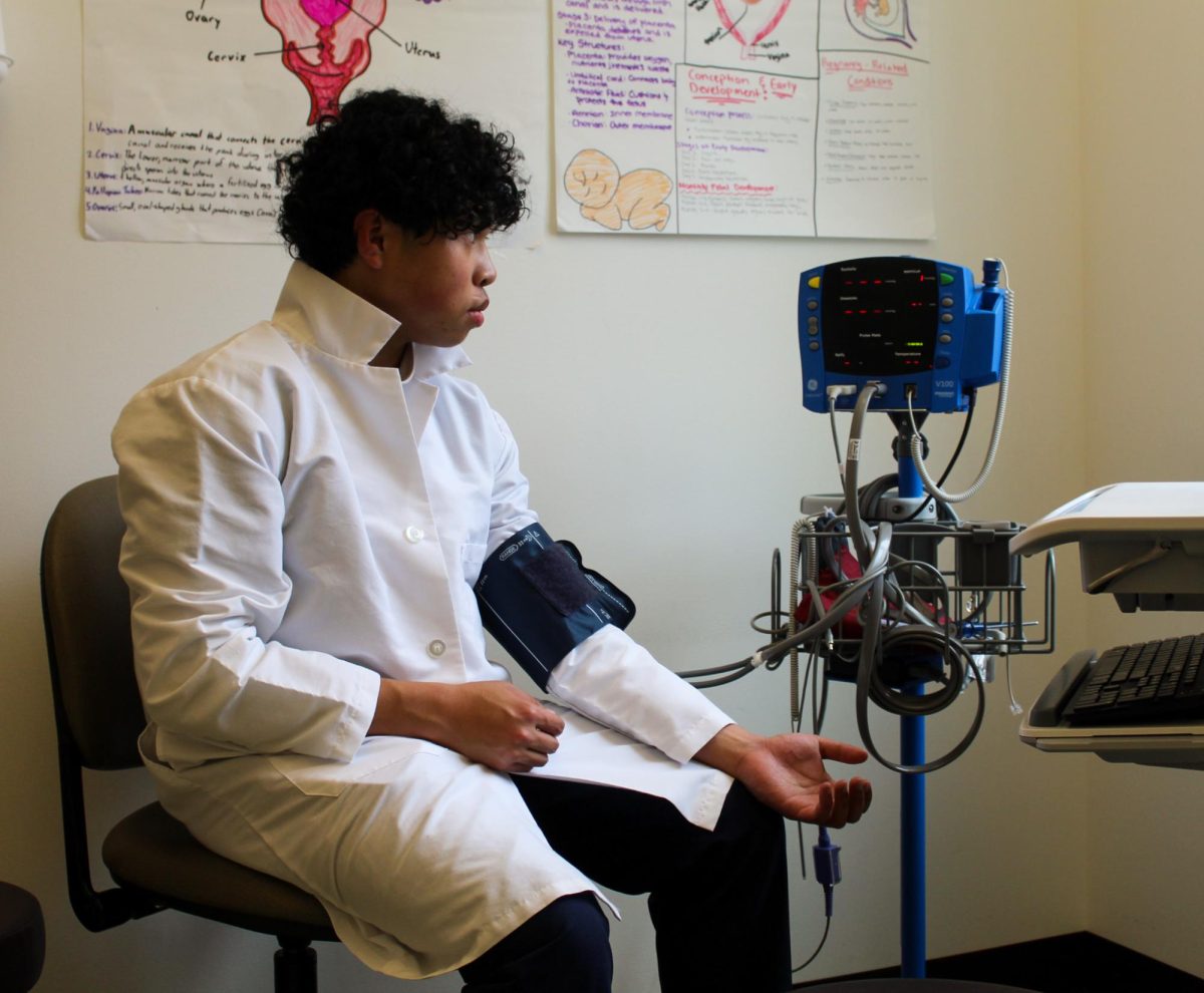 Sinaga carefully watches the numbers on the blood pressure monitor fluctuate as he waits for the cuff to deflate. The WaNIC Medical Careers classroom includes several minirooms with medical equipment, from wheelchairs and hospital beds to stethoscopes.
