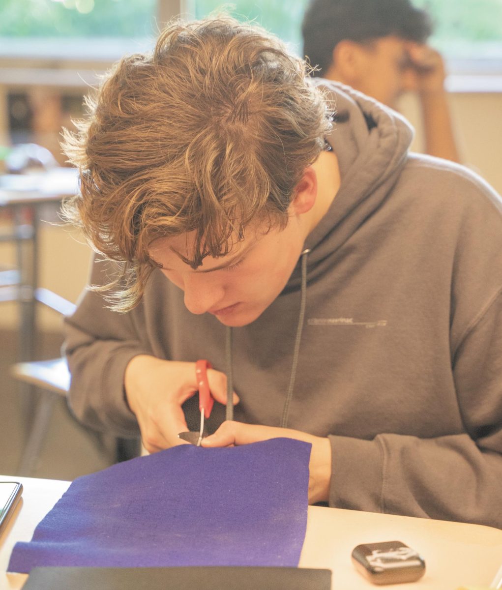 Senior Crayson Mavrinac cuts felt to create the design on his cap.