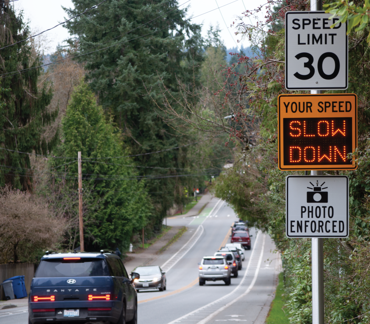 Cars drive by signage denoting a photo enforcement area for future transportable cameras along 170th St. Transportable cameras are yet to be implemented in Kenmore, but their approved zones are already marked.